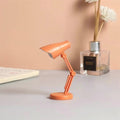 Orange Coral Mini LED Adjustable Desk Lamp with a sleek design, featuring a mix of materials including wood, plastic, and metal, suitable for stylish office and home lighting.